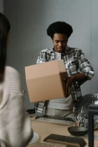 Young man packing a cardboard box, possibly in a store setting. Professional and focused.